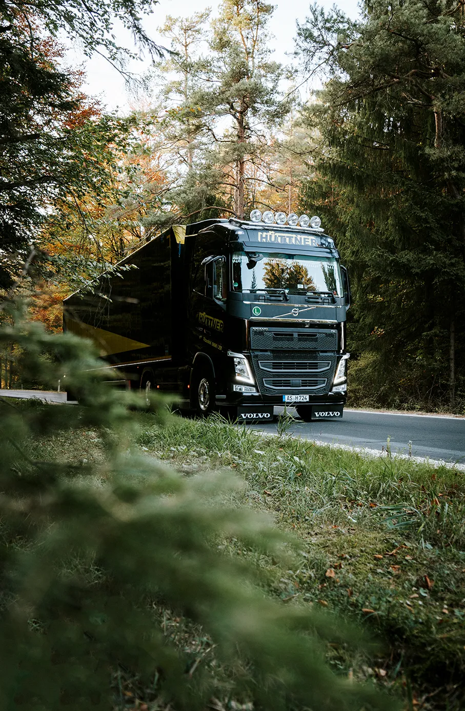 Schwarzer Hüttner-Lkw auf einer Waldstraße im Herbst