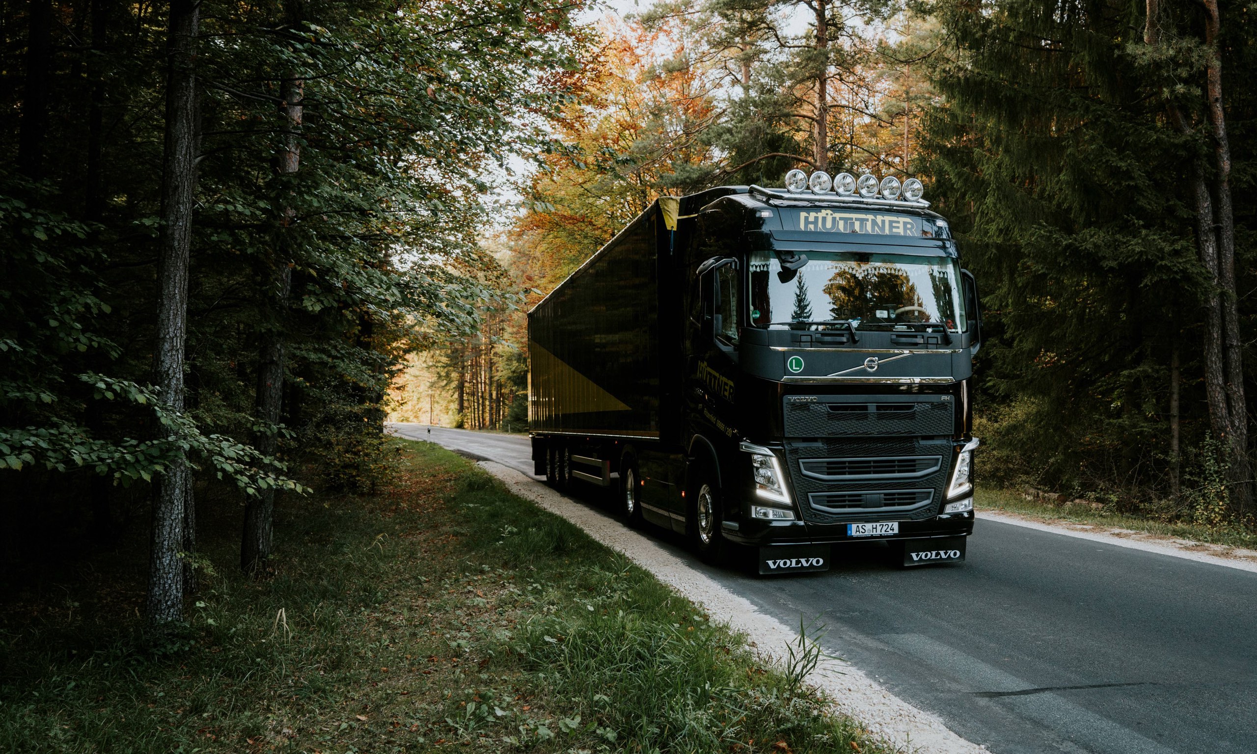Ein Hüttner-Lkw in Schwarz und Gelb auf einer Waldstraße